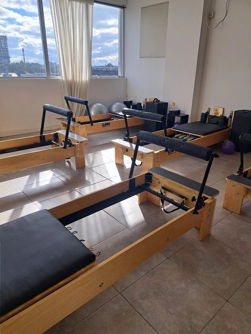 El estudio con los reformers de madera y ventanales con cortinas blancas